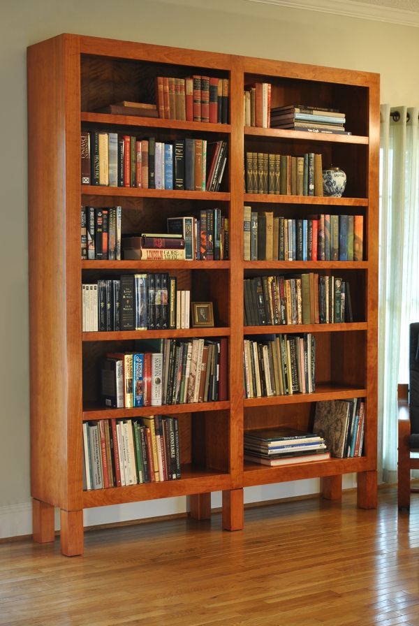 a wooden bookcase filled with lots of books on top of a hard wood floor