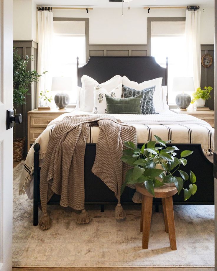 a bedroom with a bed, nightstands and potted plants in front of the window