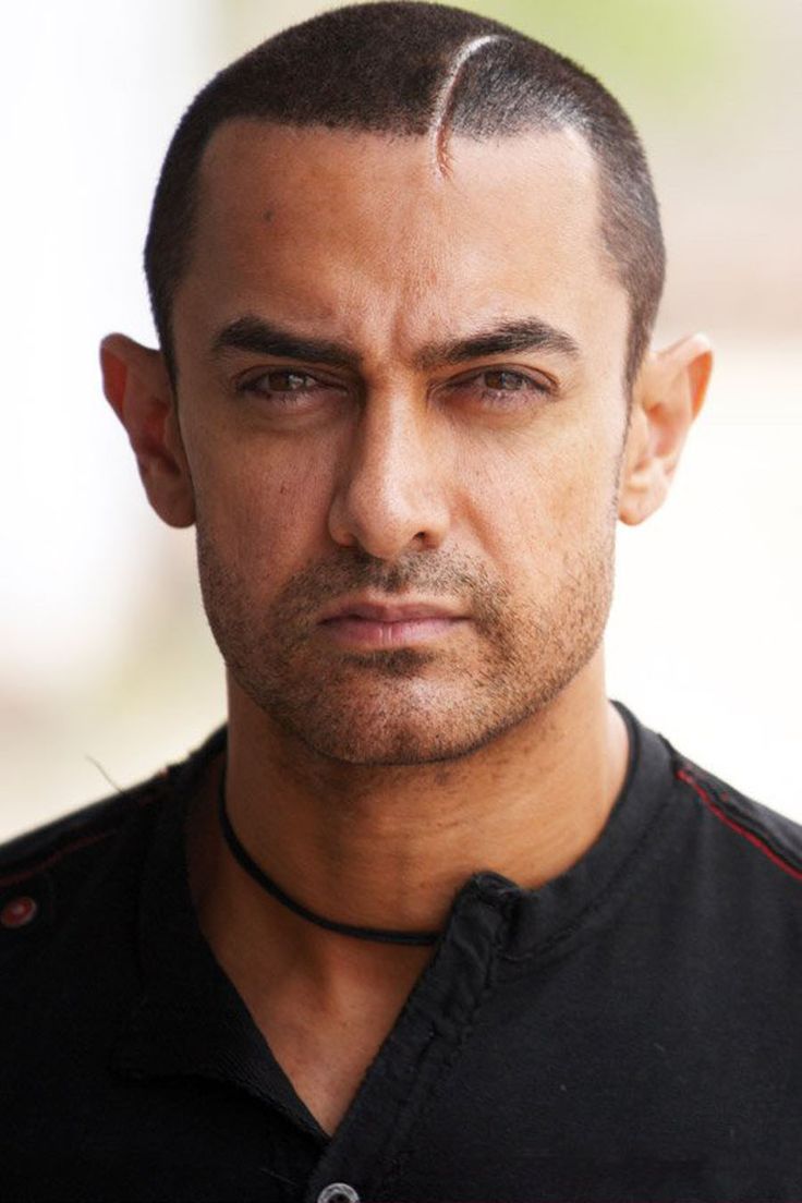 a close up of a person wearing a black shirt with a shaved haircut on his head