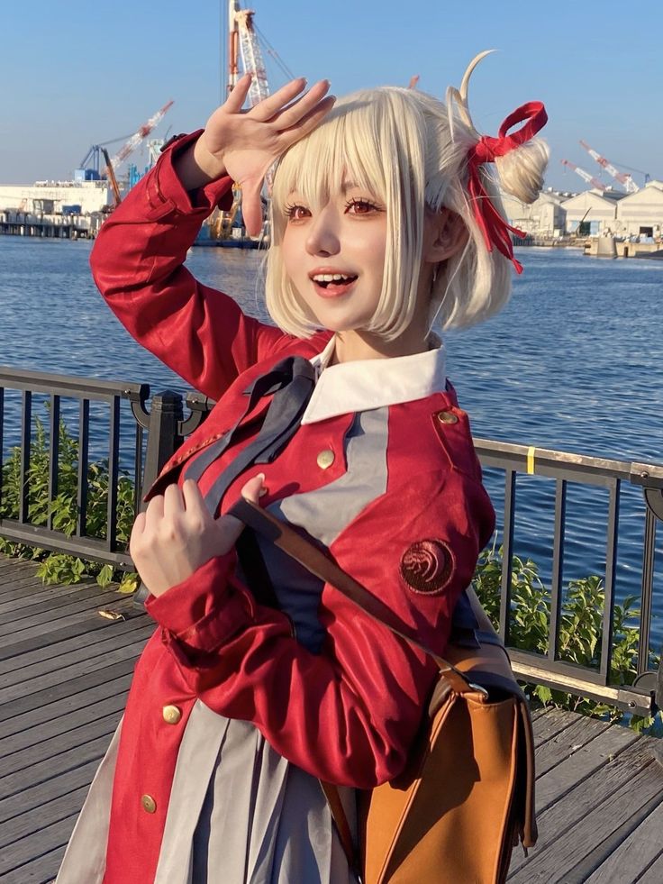 a woman with blonde hair wearing a red jacket and holding her hand up in the air