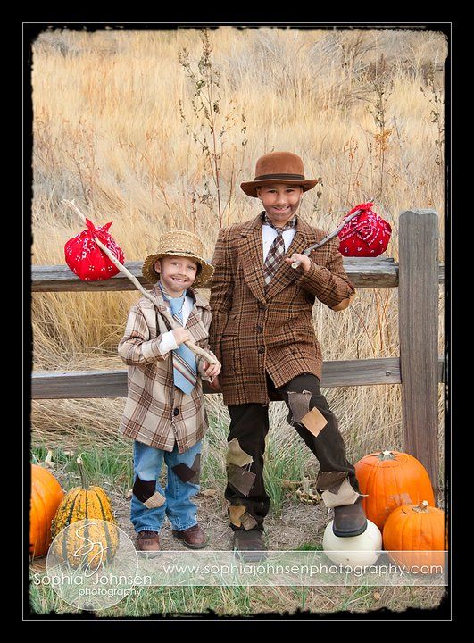 two children dressed up in costumes standing next to each other near pumpkins and hay