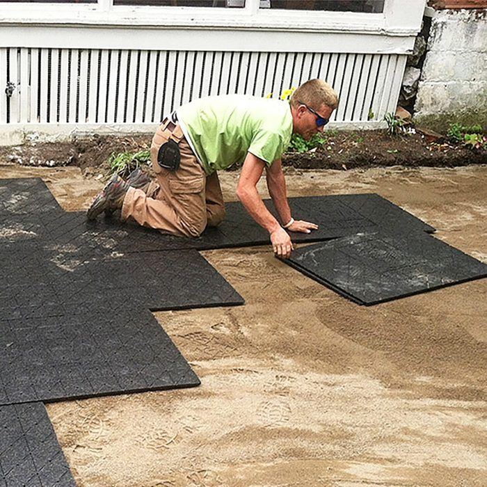 a man laying on top of black mats in front of a house