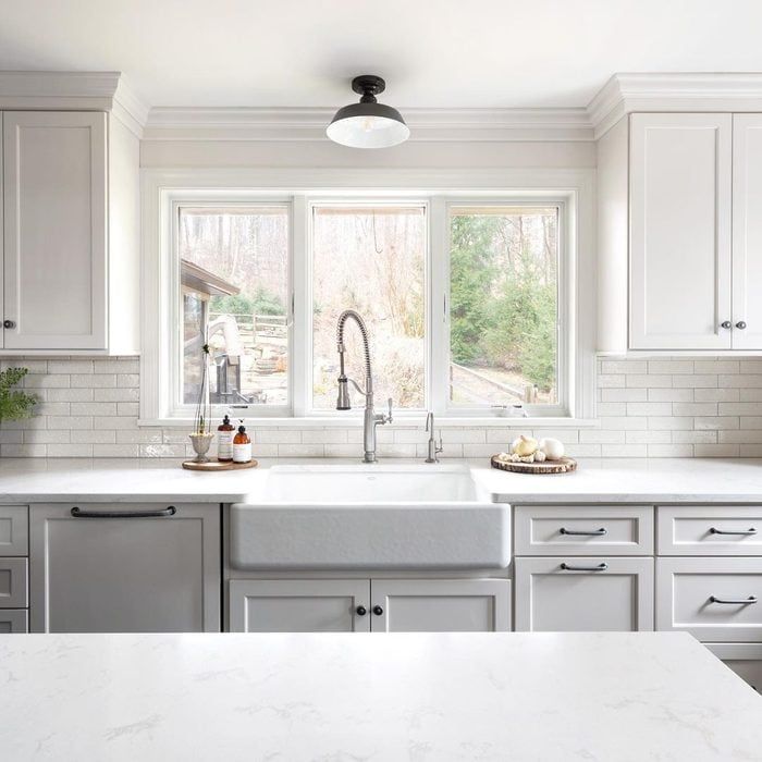 a kitchen with marble counter tops and white cabinets, along with stainless steel sink faucets