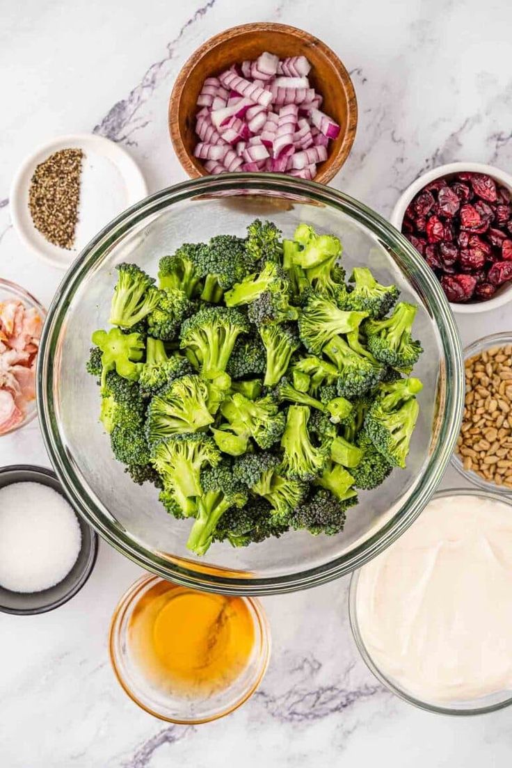 broccoli, onions and other ingredients in bowls on a marble countertop next to dips