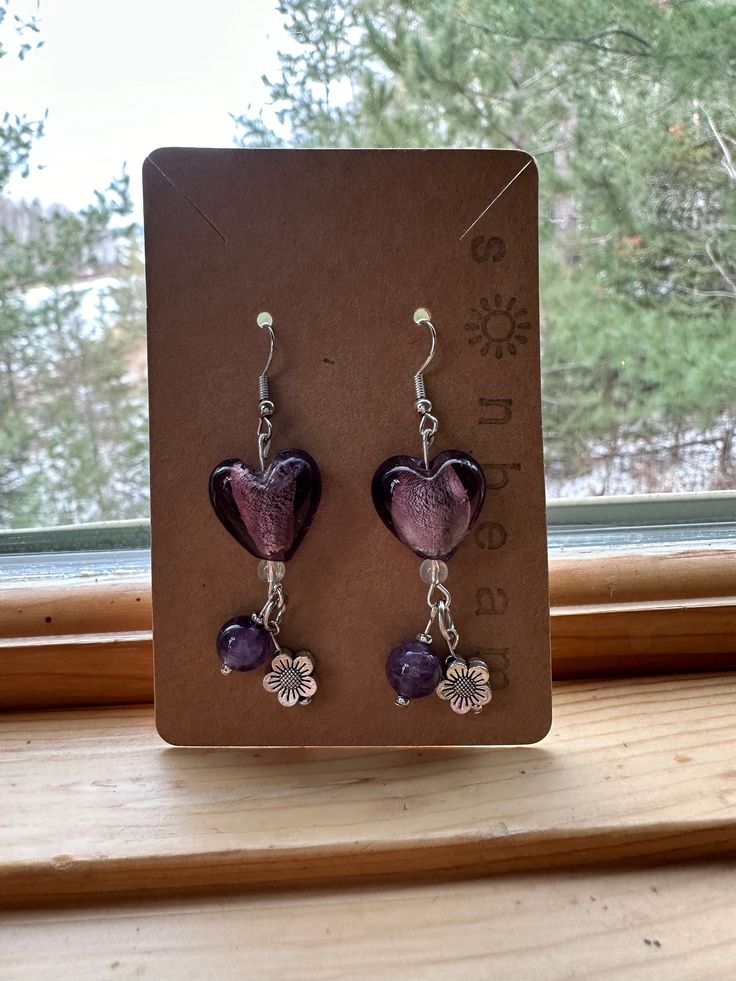 a beautiful and intricate dangle earring with purple beads and silver details worn sterling silver posts Dangle Heart Earrings, Elegant Lavender Beaded Earrings, Purple Heart Sterling Silver Jewelry, Purple Drop Chandelier Earrings As Gift, Handmade Purple Sterling Silver Earrings, Gift Heart Beads Drop Earrings, Purple Sterling Silver Heart Jewelry, Handmade Lavender Beaded Earrings For Gift, Heart Beads Dangle Earrings For Gift