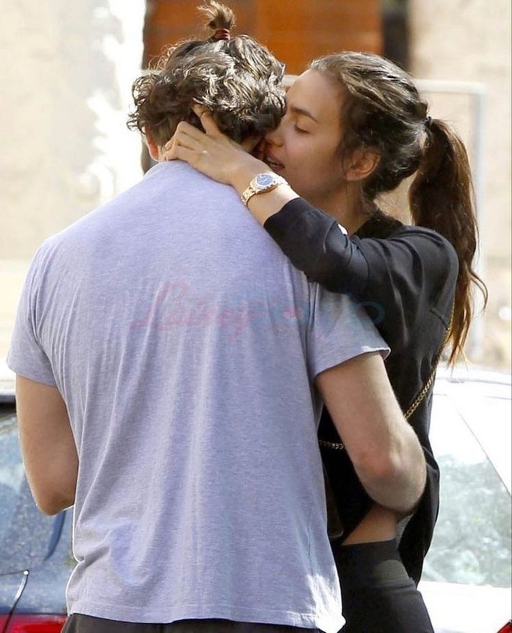 a man and woman kissing while standing next to each other in front of a car