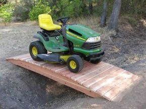 a green lawn mower sitting on top of a wooden ramp