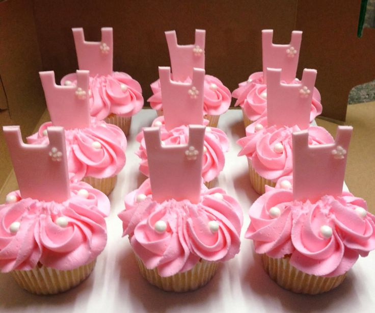 cupcakes decorated with pink frosting and pearls are arranged in the shape of letters