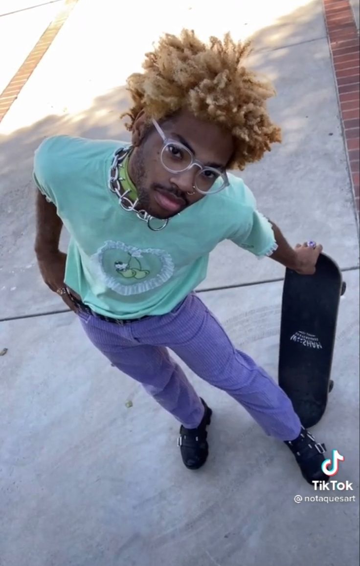 a young man holding a skateboard on the sidewalk