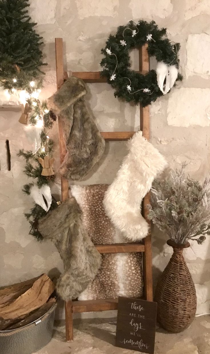 christmas stockings and wreaths are displayed on an old ladder in front of a stone wall