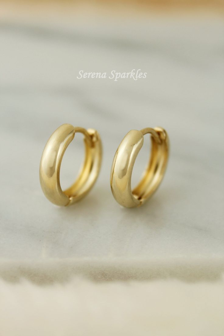 10k Solid Gold Huggie Hoop Earrings. These Real Gold Huggies are Plain and Simple and are Comfortable to wear all Day. Care for your sensitive ears Nickel free, Hypoallergenic Huggie Earrings. Metal: Solid Gold Gold Purity: 10k Stamp: 10k Dimensions: Thickness: 3mm Inner Diameter: 9.3mm Outer Diameter: 12.8mm Post Gauge: 0.85mm BUYING OPTIONS Single Piece - Refers to 1 Individual Huggie One Pair - Refers to 2 Individual Huggies PACKAGE Can be Gift packed on request. Gift packaging includes Jewel Gold Huggies, Eco Friendly Jewelry, Nose Stud, Huggie Hoop Earrings, Gift Packs, Gold Hoops, Jewelry Earrings Hoops, Huggies Earrings, Real Gold