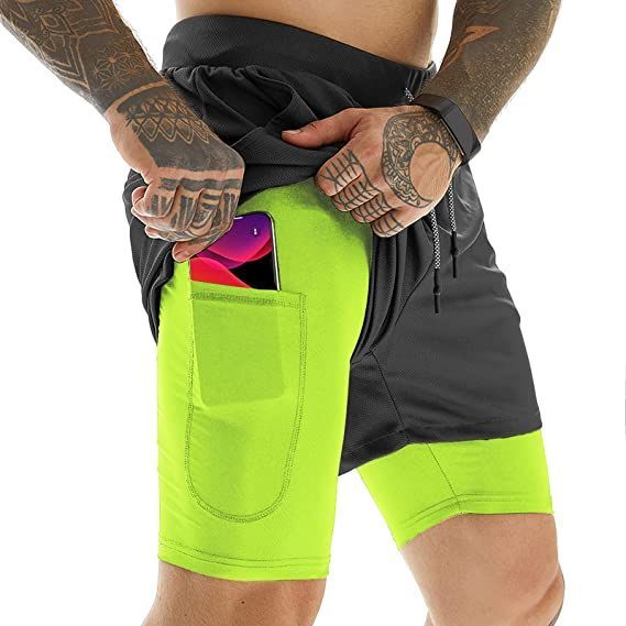 a man wearing neon green shorts and holding his cell phone in his pocket with both hands