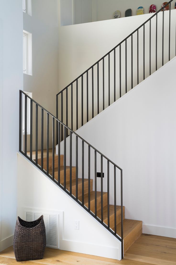 a black and white stair case next to a brown basket on the floor in front of a staircase