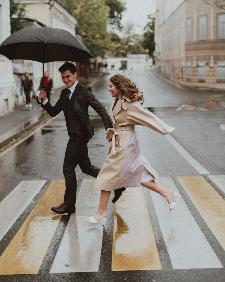 a man and woman crossing the street with an umbrella