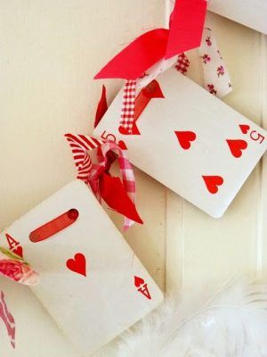 two playing cards with red hearts tied to them