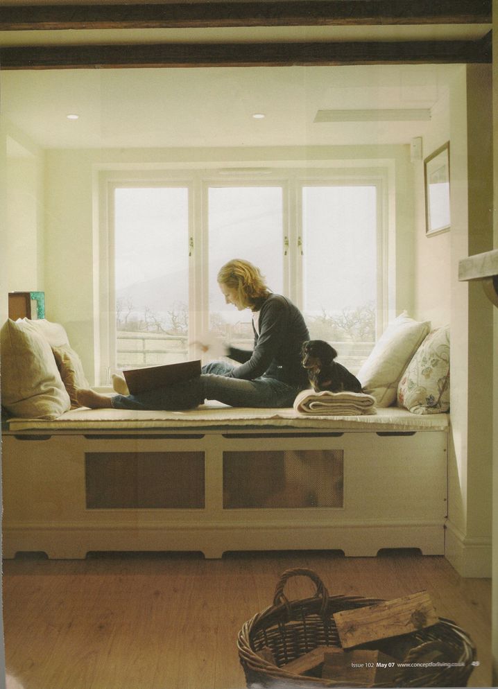 a woman sitting on top of a window sill next to a basket filled with books