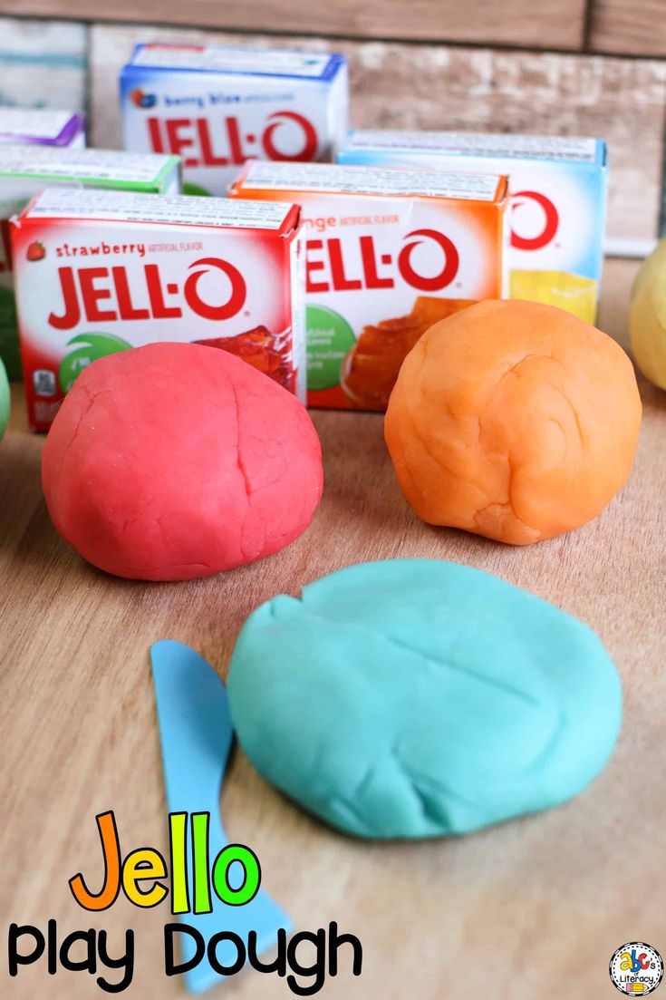 colorful play dough sitting on top of a wooden table next to boxes of jello