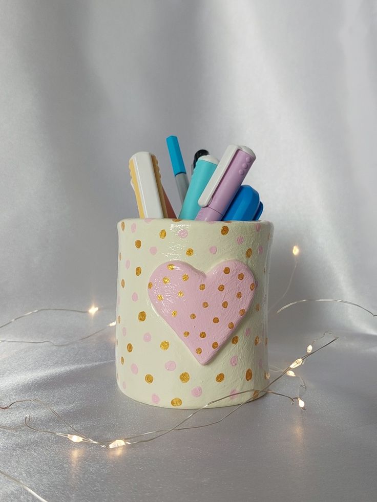 a cup filled with pens and markers on top of a table