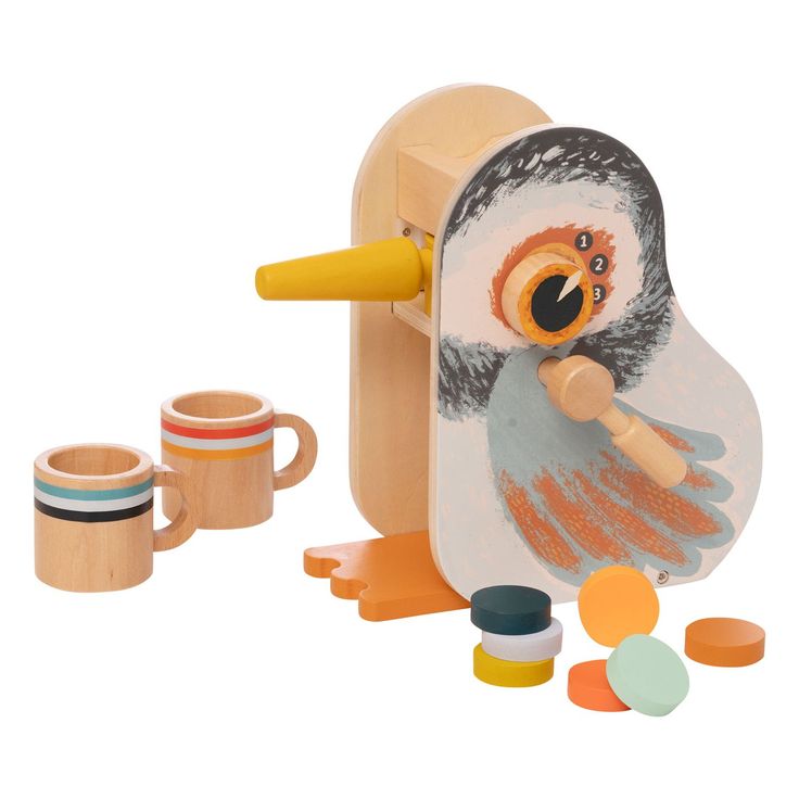 a wooden penguin with two mugs next to it and some other toy items on the ground