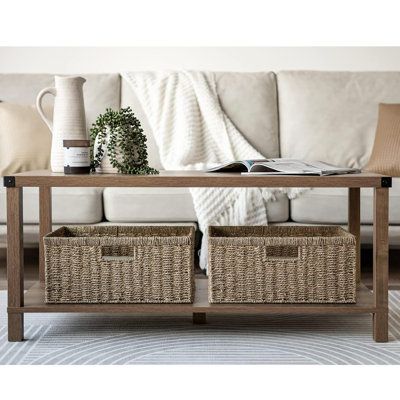 a coffee table with two baskets underneath it on a rug in front of a couch