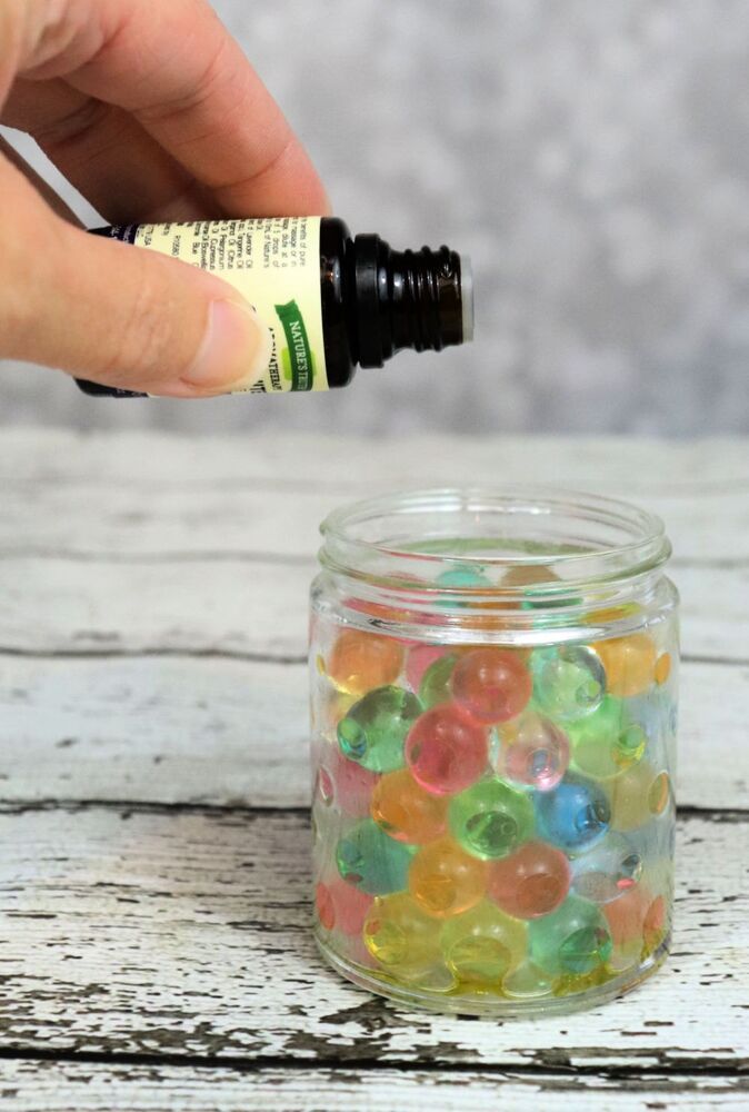 a hand is holding a small bottle filled with gummy bears and an essential oil