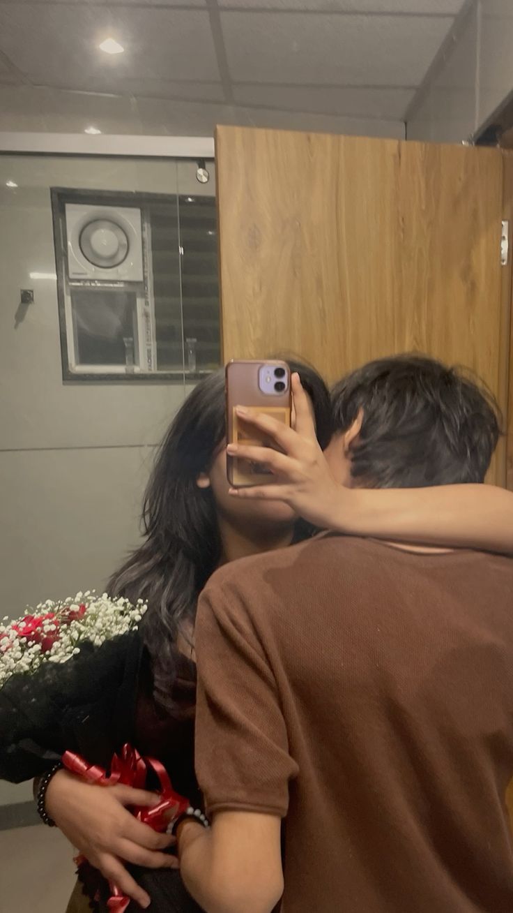 a man and woman taking a selfie in front of a mirror with flowers on it