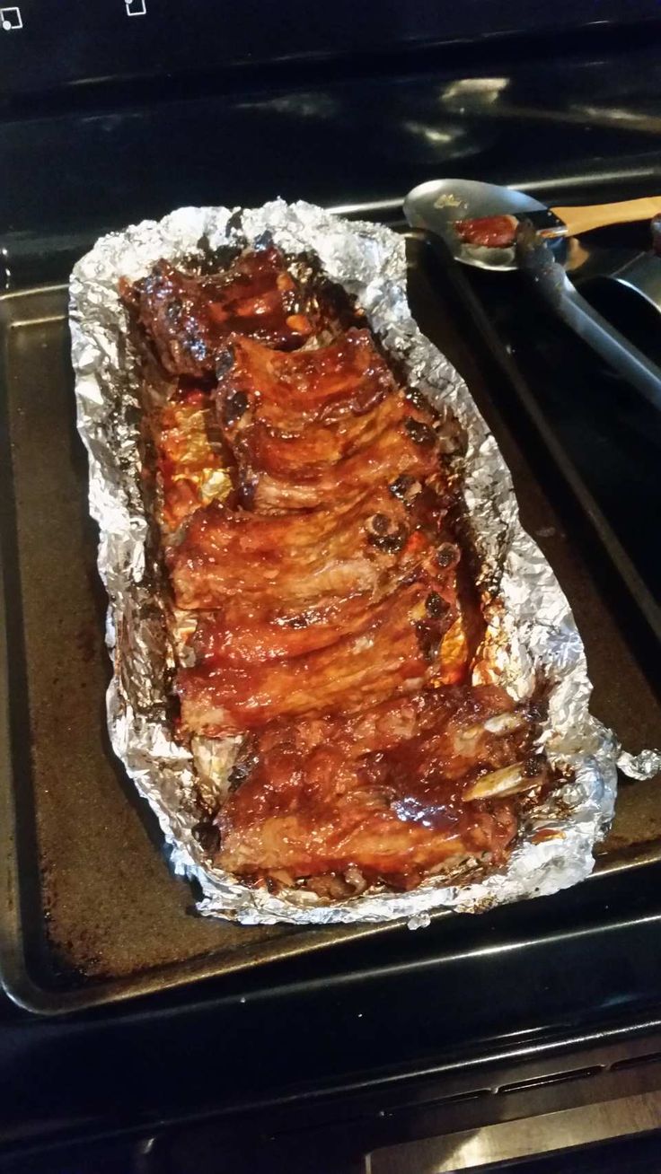 the meat is being cooked in the oven with tongs next to it and on top of the grill