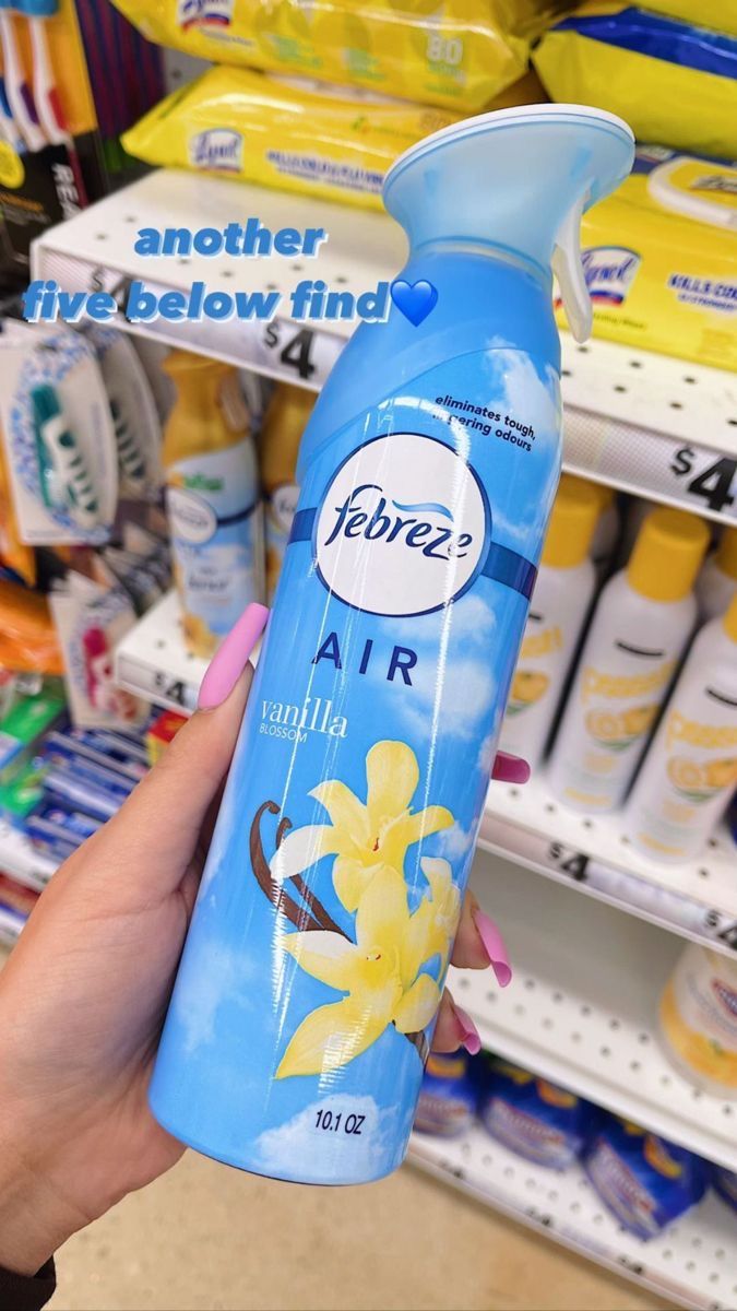 a person holding up a bottle of air freshener in a store aisle with other products on the shelves