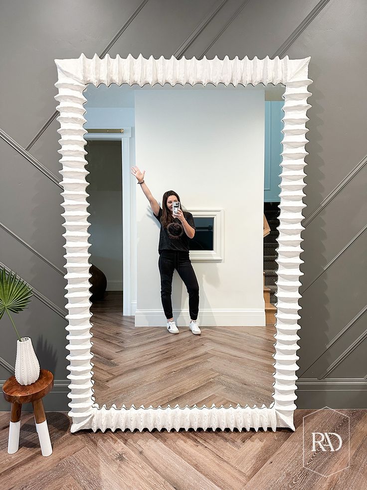 a woman taking a selfie in front of a large mirror with white strips on it