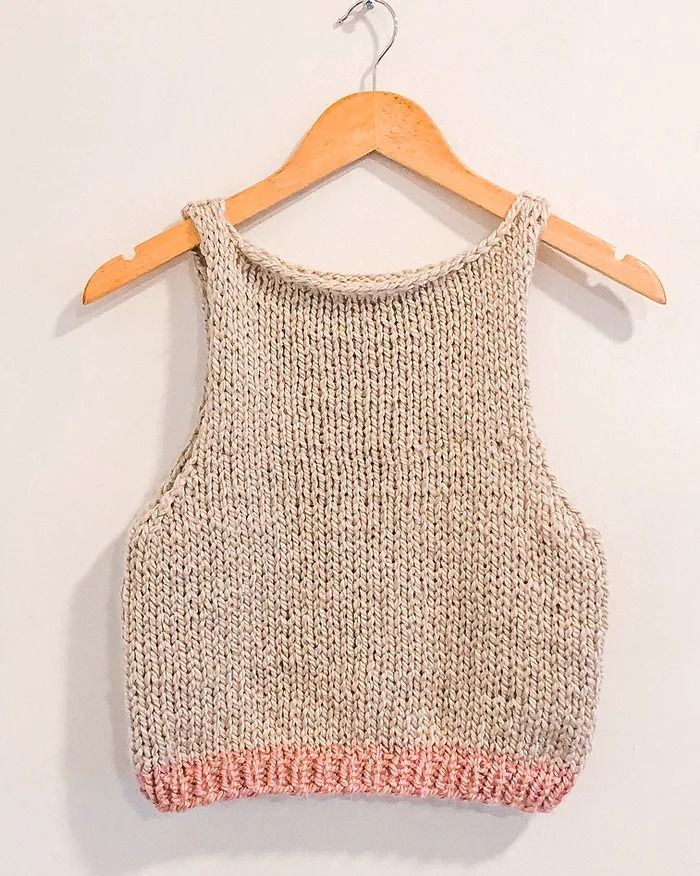 a knitted top hanging on a wooden hanger