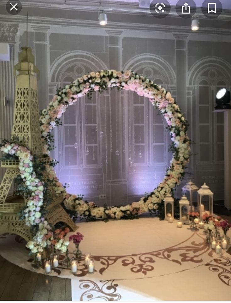 a table with flowers and candles on it in front of a wall that has an eiffel tower