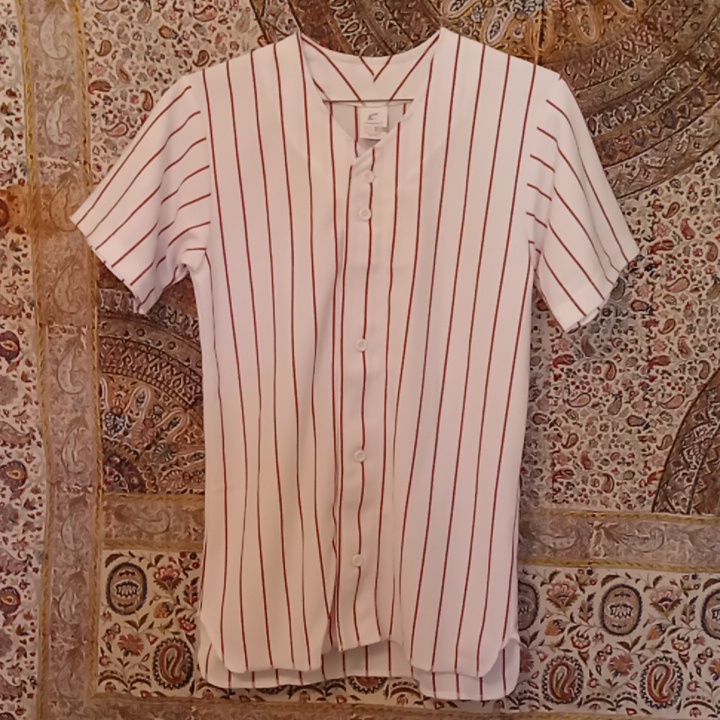 a baseball jersey hanging on a wall with an ornate pattern in the backgrouund