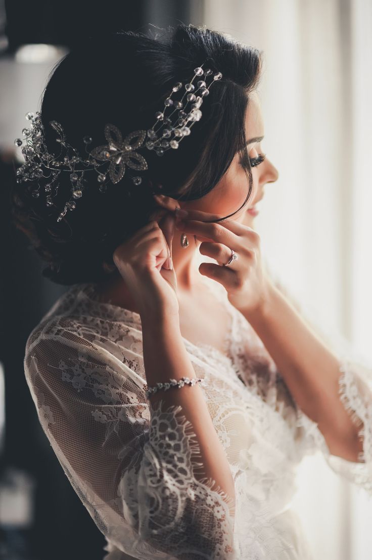 a woman wearing a tiara and holding her hands to her face while looking out the window