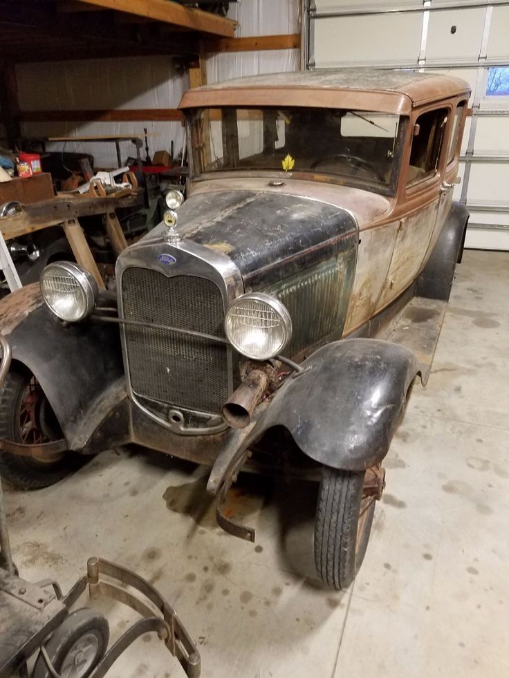 an old car sitting in a garage next to some tools and other items on the floor