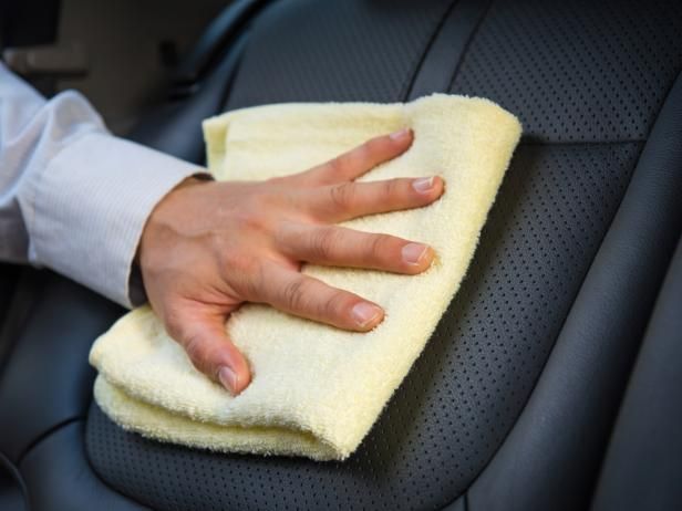 a person wiping down the back seat of a car with a microfiber cloth