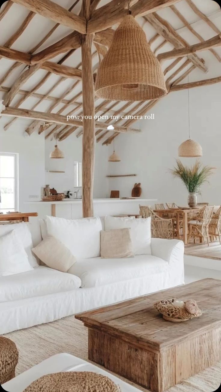 a living room filled with white furniture and wooden beams on the ceiling is covered in wicker