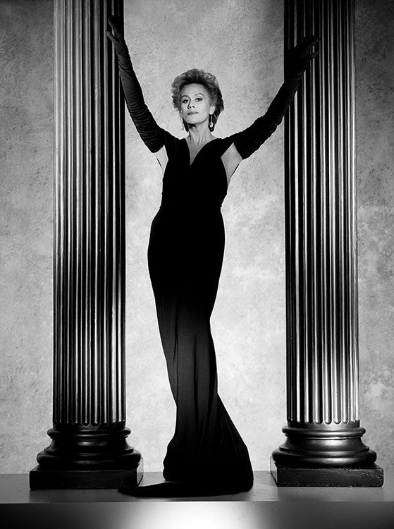 an old photo of a woman standing in front of some pillars with her arms outstretched