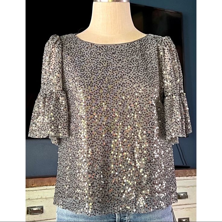 New With Tags Size Small This Pretty Grey Blouse By Maeve At Anthropologie Is Covered In Sparkling Silver Sequins. The Short Top Has Romantic Tiered Flutter Sleeves. The Back Has A Sweet Opening With A Button Closure. It Is Fully Lined. In The Pictures The Top Is Paired With Re/Done 80’s Jeans (Sizes 26,29), Available For Purchase Separately In My Store. Measurements Laying Flat: Length 21 1/4” Bust 19 1/4” Metallic Tops For Festive Summer Occasions, Metallic Top For Festive Summer Events, Silver Tops For Spring Party, Metallic Silver Top For Night Out In Spring, Silver Party Tops For Spring, Metallic Sequin Tops For Spring, Metallic Silver Top For Spring Night Out, Silver Sparkling Tops For Summer, Festive Silver Elegant Blouse