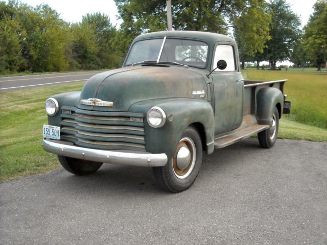 an old pick up truck is parked on the side of the road