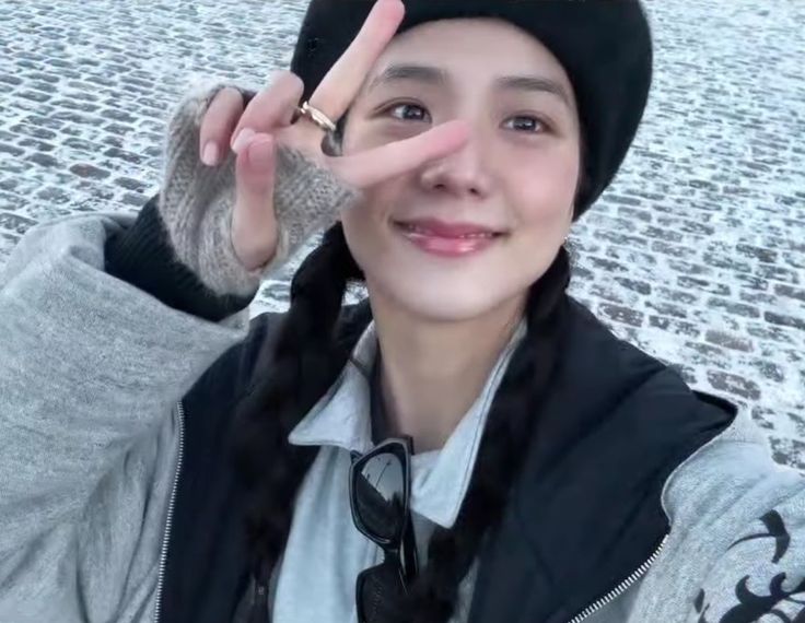 a young woman making the peace sign with her fingers while standing in front of snow covered ground