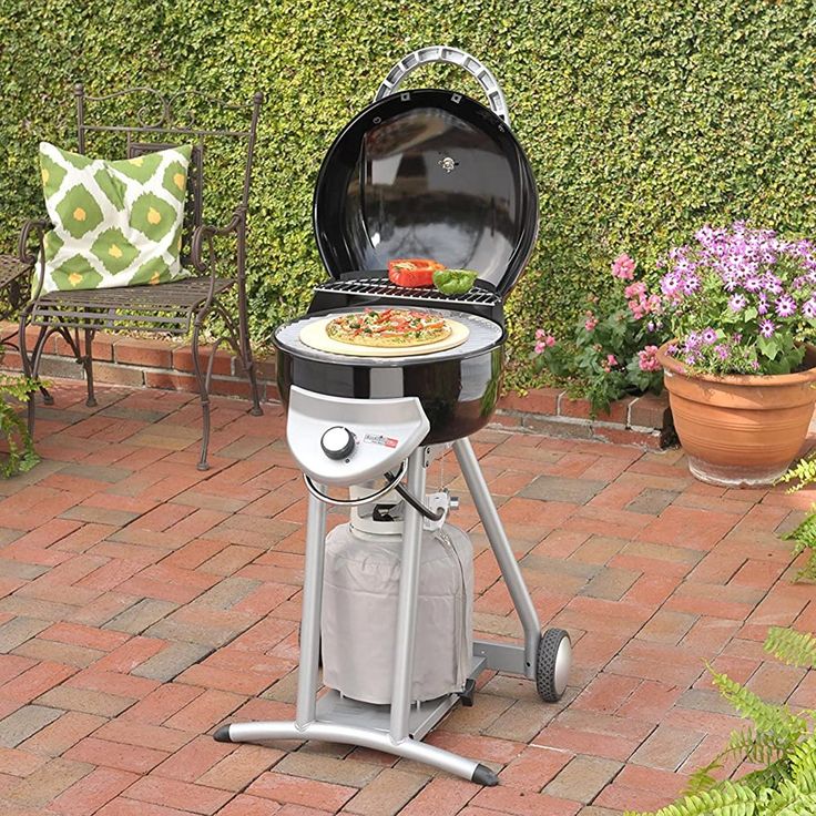 an outdoor grill with a pizza on the top and side burner in front of it