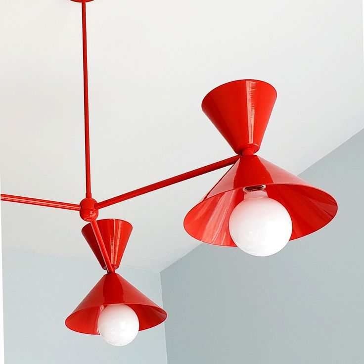 two red ceiling lights hanging from the ceiling in a room with white walls and ceilings