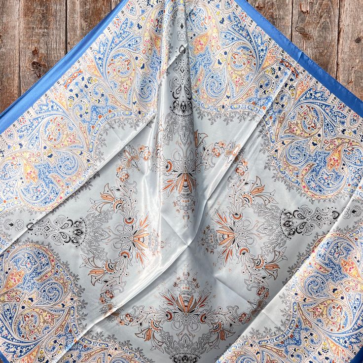 Our classic wild rag/scarf in blue with a decorative floral pattern. A perfect square - measuring 35"x35". Adding that extra touch of a western style to your outfit. 100% soft silk feeling polyester is durable to keep you warm in the cold and fashionable for any occasion. Plus it's machine washable! Additional accessories are available- (Please see our slide options on our site) Leather slides Western concho slides Crystal concho slide Buckle slides Elegant Blue Scarf With Bandana Print, Bohemian Blue Bandana Scarf, Bohemian Blue Scarf Bandana, Blue Silk Scarf With Paisley Print, Outfit Western, Perfect Squares, Wild Rag, Leather Slides, Western Style