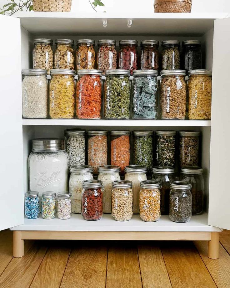 an open cabinet filled with lots of different types of food and spices on top of wooden floors