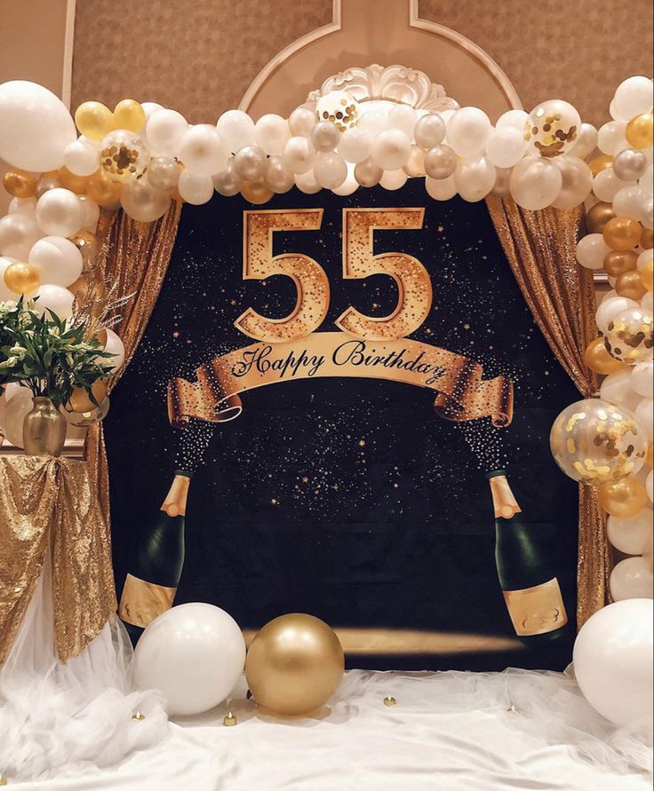 a 50th birthday backdrop with balloons and streamers in gold, white and black colors