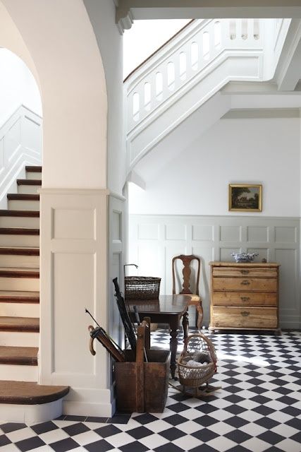 a room with black and white checkered flooring next to a stair case in an old house