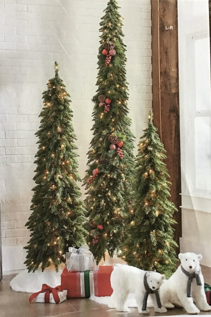 three small christmas trees with presents on the floor next to them and two polar bear figurines