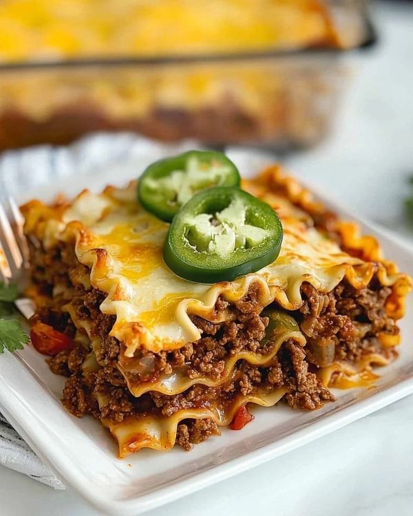 a white plate topped with lasagna covered in meat and cheese next to a fork