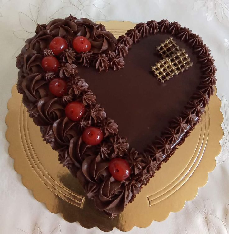 a heart shaped cake with chocolate icing and cherries