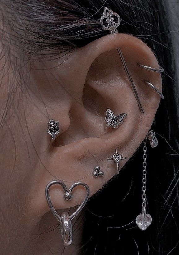 a woman with multiple ear piercings attached to her ears and behind the ear is a heart